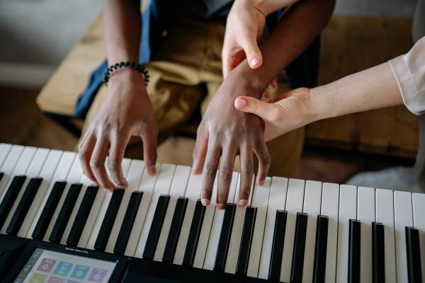 Teacher guiding hand during piano lessons