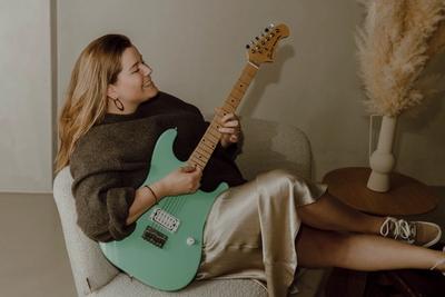 a woman is sitting in a chair holding a green electric guitar .