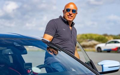 a man wearing sunglasses is standing next to a car .