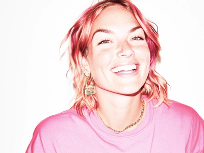 a woman with pink hair and a pink shirt is smiling