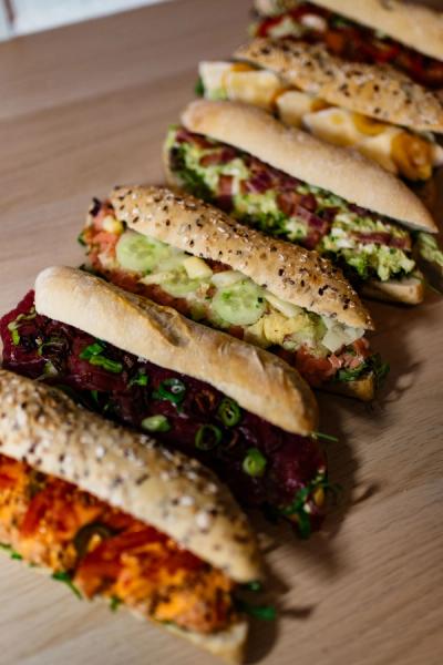 a row of sandwiches with different toppings on a wooden table .
