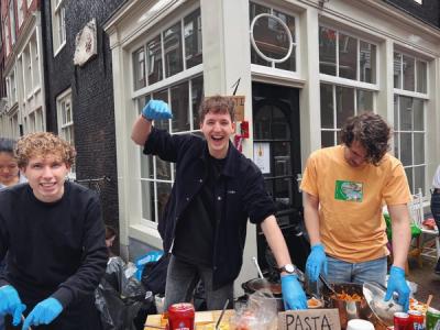 a group of young people wearing blue gloves are preparing food in front of a building .
