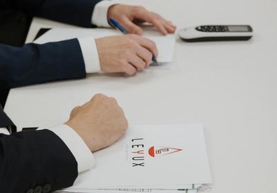 a man in a suit is sitting at a table writing on a piece of paper .