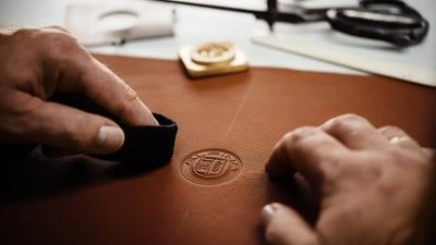 a person is stamping a Alpina logo on a piece of leather .