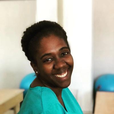 a woman in a blue scrub is smiling for the camera .