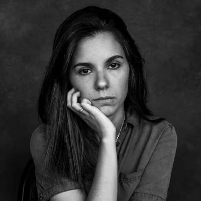 a black and white photo of a woman with her hand on her chin .