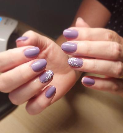 a woman 's nails are painted purple with white flowers on them