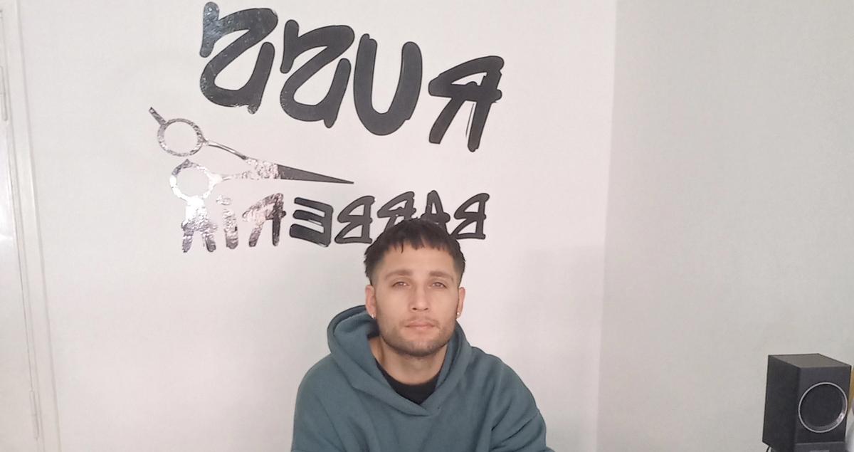 a man is sitting in front of a wall with scissors on it .