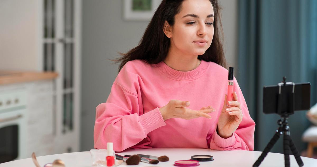 a woman is sitting at a table holding a bottle of nail polish .
