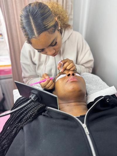 a woman is applying eyelash extensions to another woman 's eye .