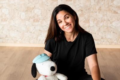 Flor is sitting on the floor holding a stuffed snoopy dog