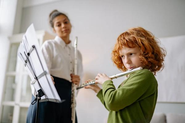Teacher watching young child play flute