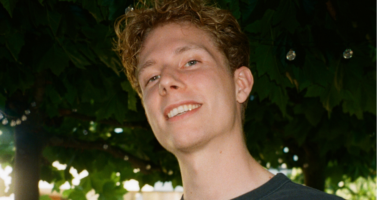 a young man with curly hair is smiling for the camera