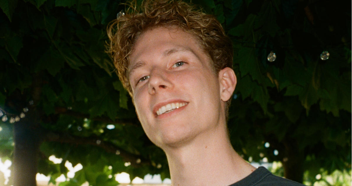 a young man with curly hair is smiling for the camera