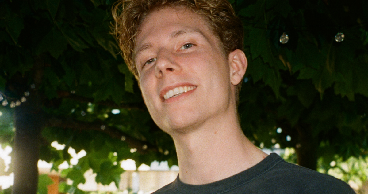a young man with curly hair is smiling for the camera
