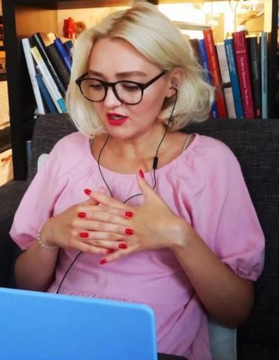 a woman wearing glasses and red nails looks at a laptop screen