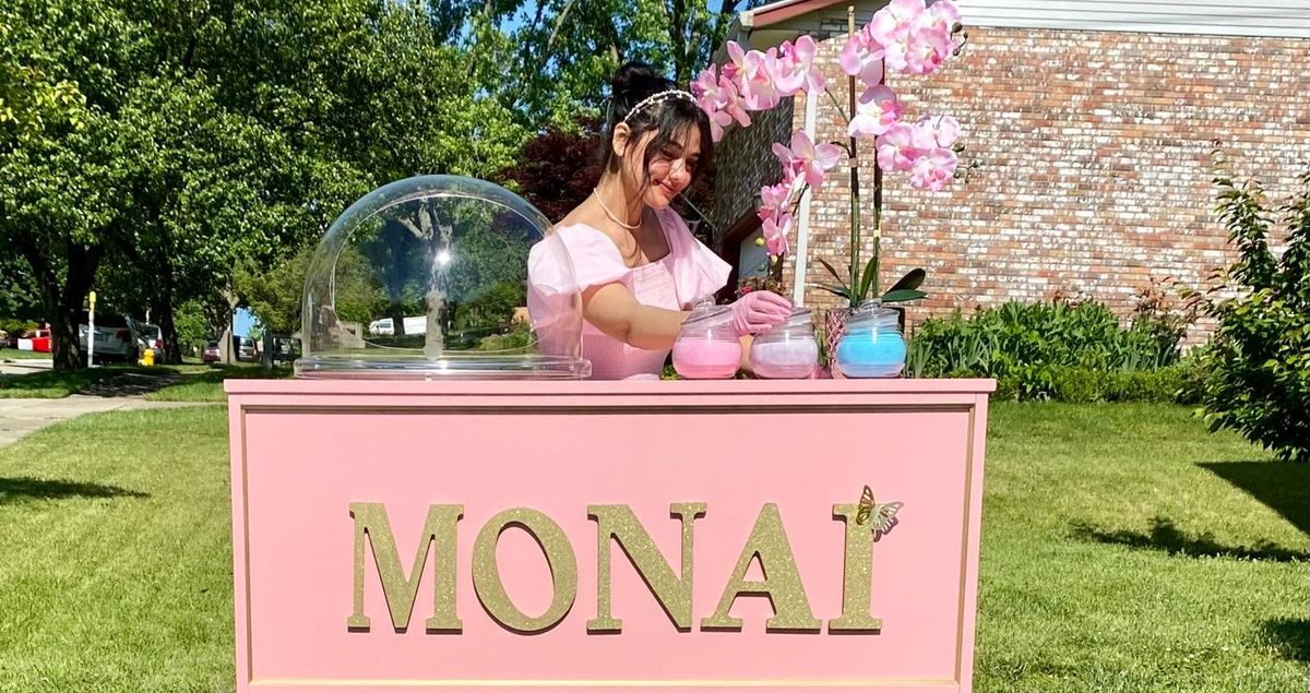 Ibithal standing behind a pink cotton candy bar.