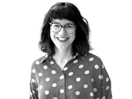 a woman wearing glasses and a polka dot shirt smiles