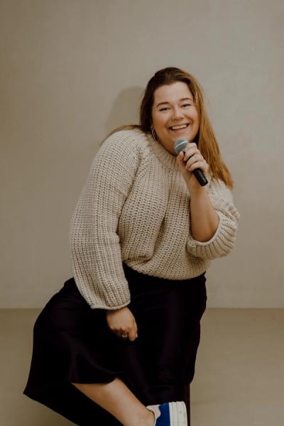 a woman in a sweater is singing into a microphone