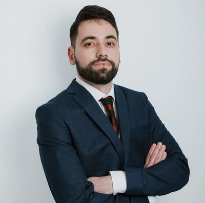 a man in a suit and tie is standing with his arms crossed .