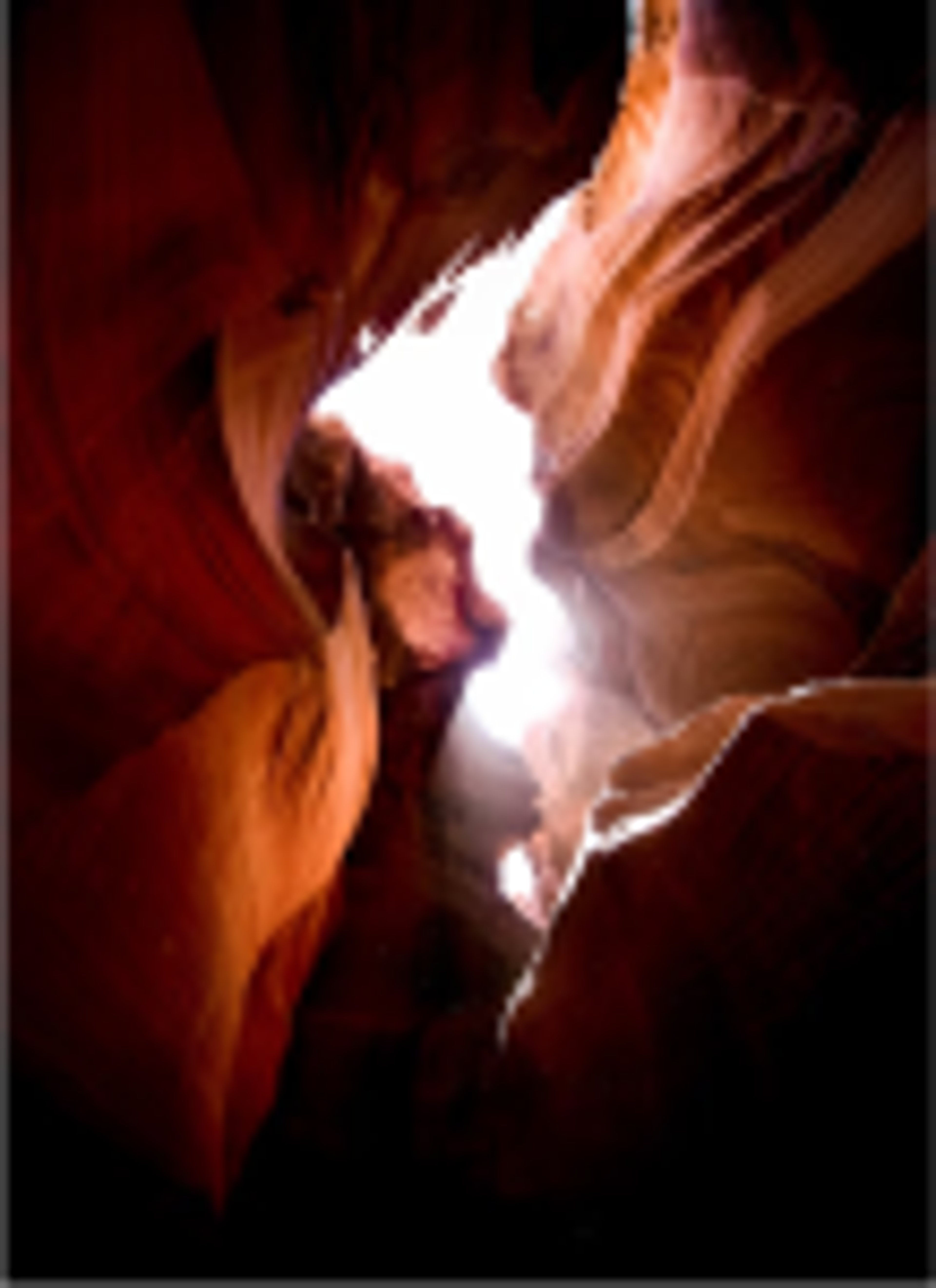 The view from the ground looking up into the space between two orange mountains in the daylight.