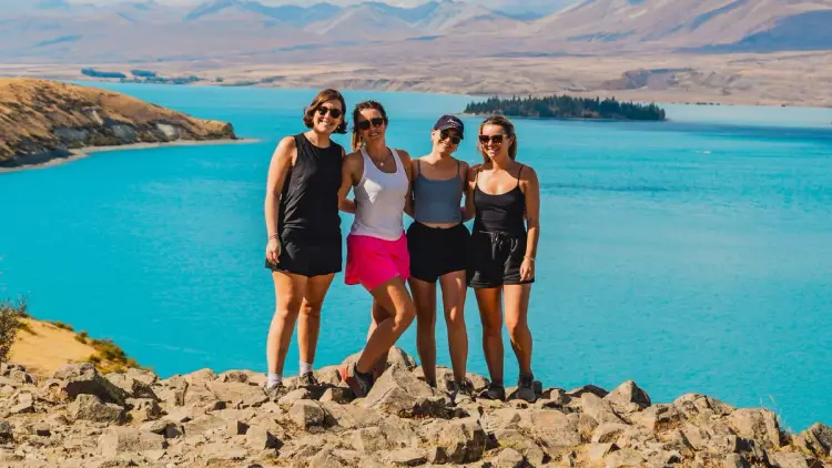 A group of young women pose for a photo in front of Lake Tekapo