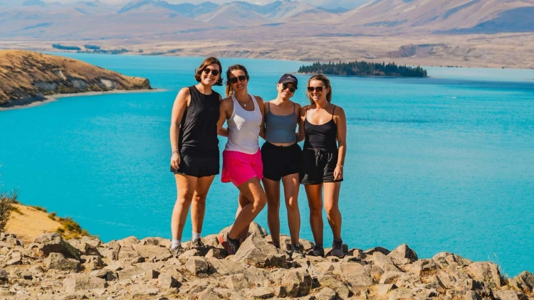 A group of young women pose for a photo in front of Lake Tekapo