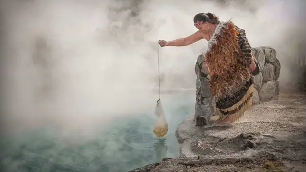 Woman removing boiled food from a hot pool