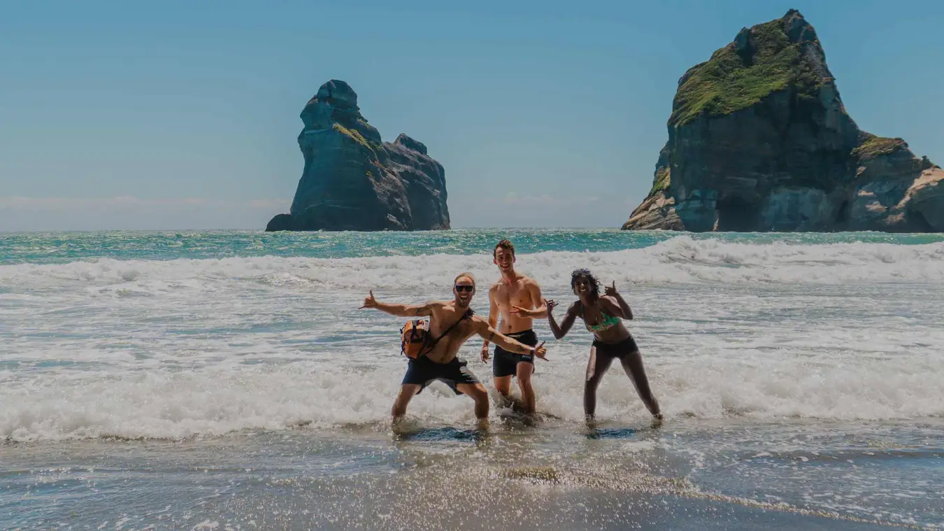 Group of friends pose for a photo on Wharariki Beach