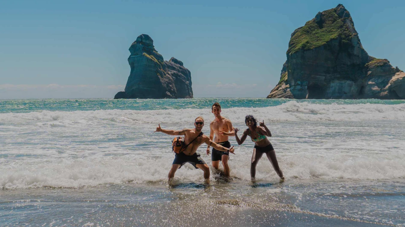 Group of friends pose for a photo on Wharariki Beach