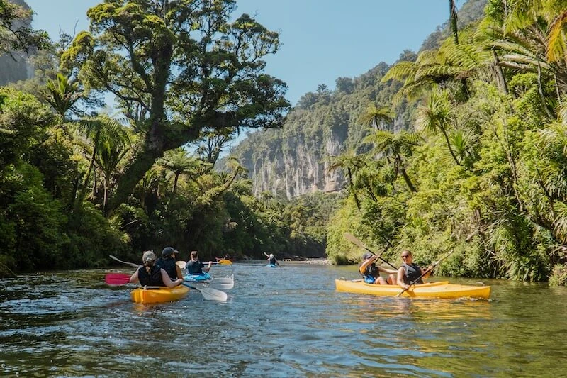 Photo of one of the best summer activities in New Zealand's South Island - kayaking in Punakaiki. Photo of a group of young travellers on an adventure road trip of New Zealand.
