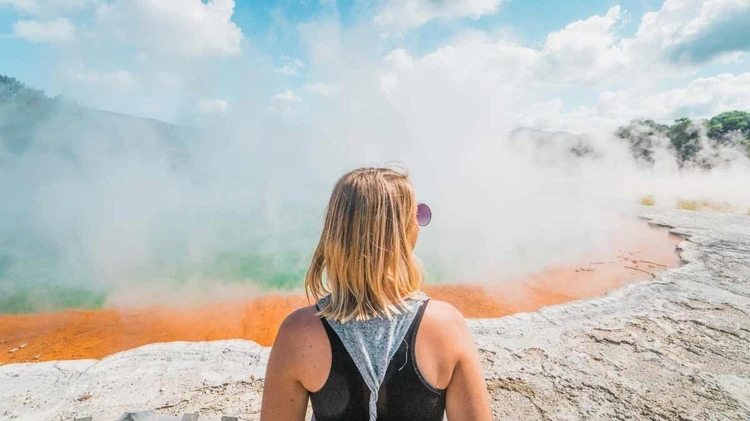 Woman standing in front of the Champagne Pool at Wai-O-Tapu