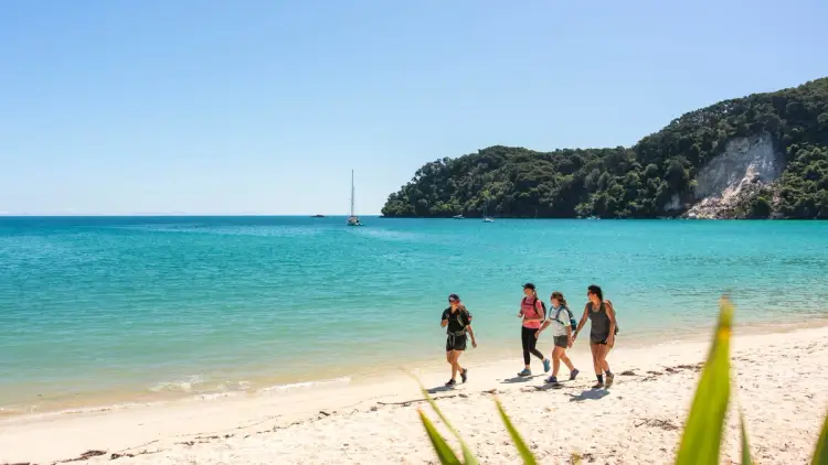 Friends hiking on the beach at Abel Tasman