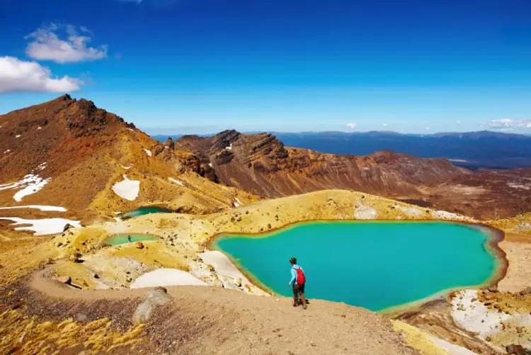 Person walking next to an alpine lake