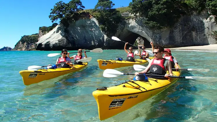 Group of people kayaking at Cathedral Cove in New Zealand