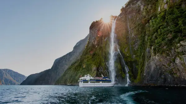 Boat under a waterfall in Milford Sound