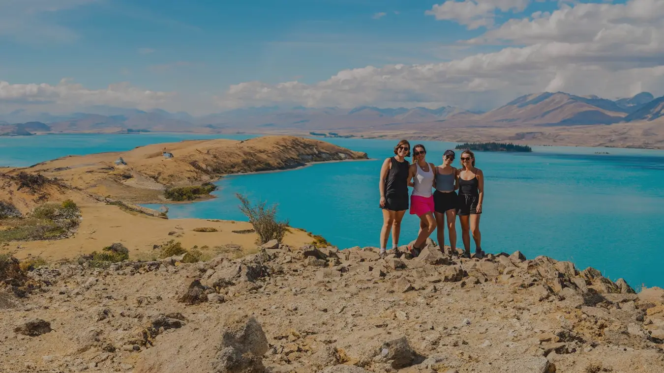 Group of women pose for a photo in front of Lake Tekapo