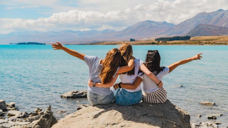 Three friends with their arms around each other at Lake Tekapo in New Zealand