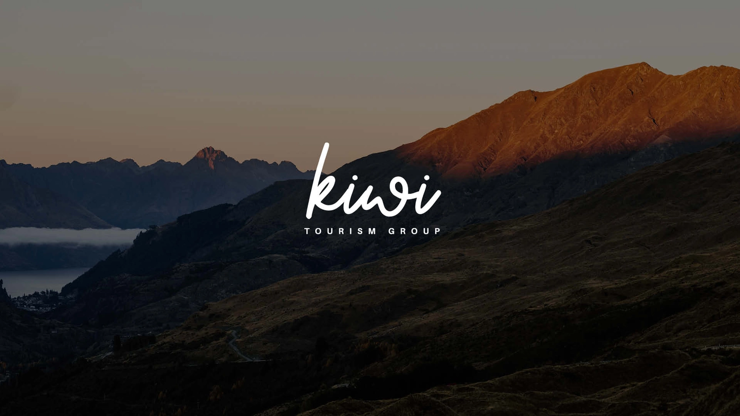 Kiwi Tourism Group logo over a photo of some mountains in New Zealand