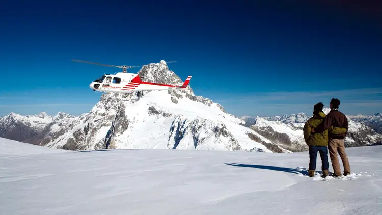 Couple look at a helicopter on Mount Cook