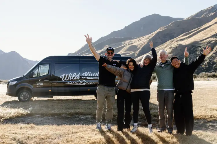 a group of people cheering in front of wild kiwi bus