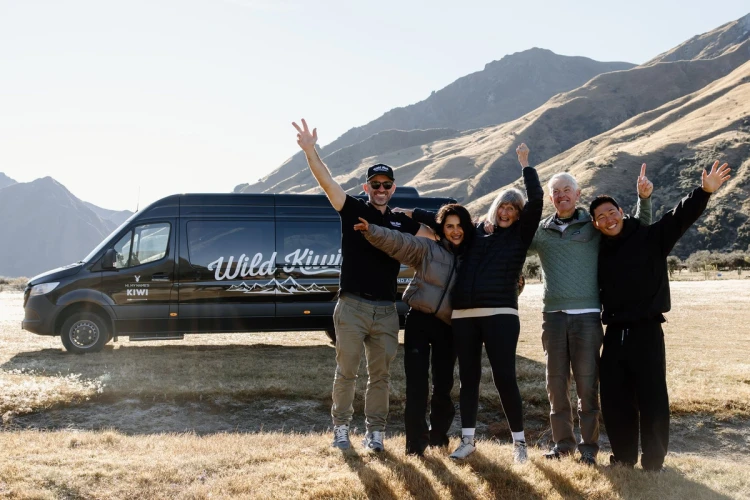 a group of people cheering in front of wild kiwi bus