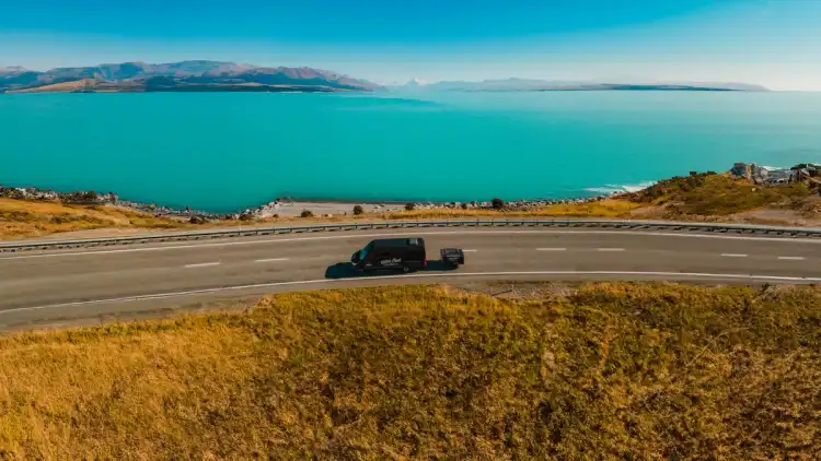 Wild Kiwi vehicle driving in front of Lake Tekapo