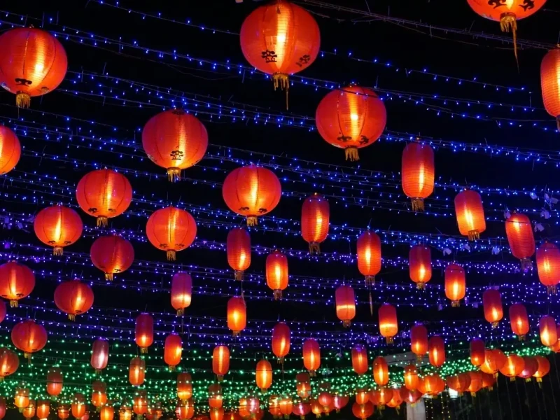Red lanterns glowing at night during Lunar New Year celebrations, with festive lights overhead, capturing the atmosphere of Chinese New Year lantern festivals and New Year traditions.