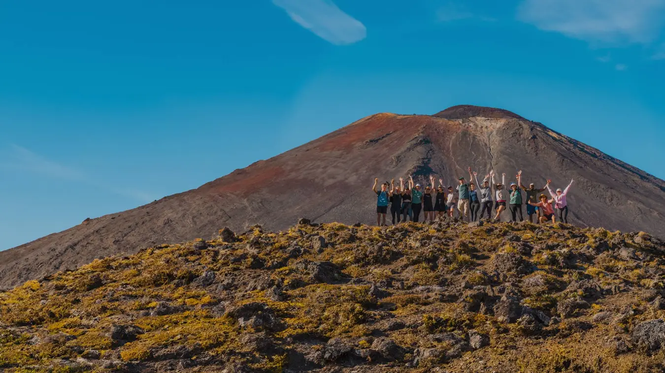 Group of friends pose for a photo in front of a mountain on the Tongariro Crossing