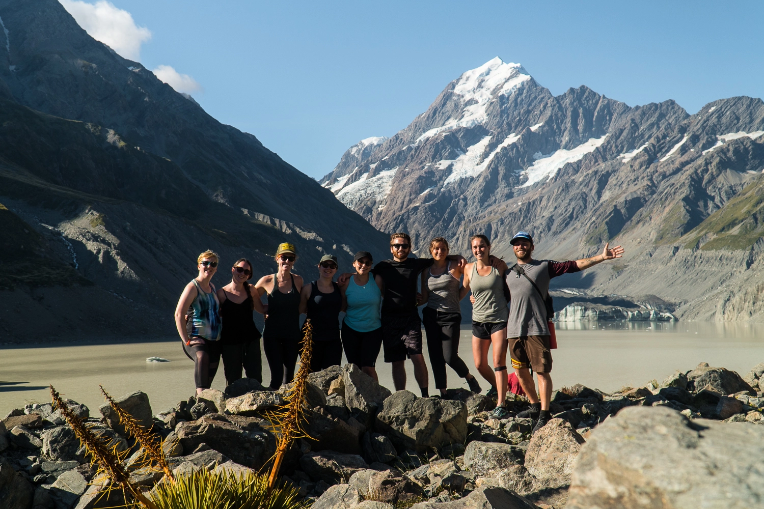 a small group of people take a pose with a beautiful mountain background