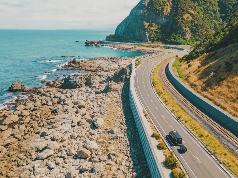 Aerial photo of a south island coastal road near empty with a Wild Kiwi tour van driving along during Spring time in New Zealand.