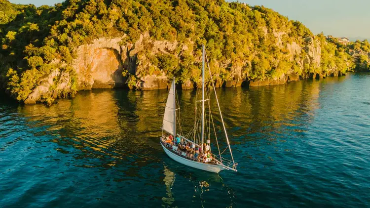 Yacht sailing next to maori rock carvings on Lake Taupo