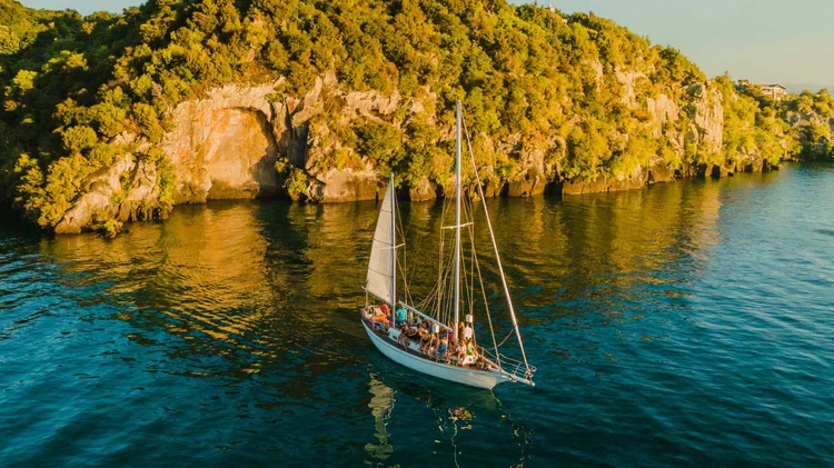 Yacht sailing next to maori rock carvings on Lake Taupo