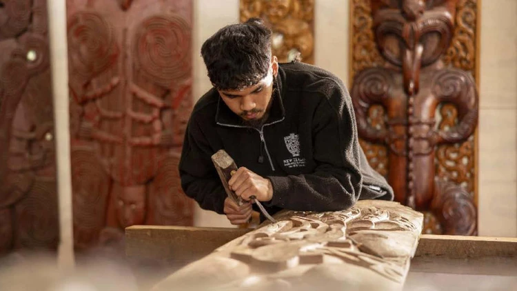 Man creating a traditional Maori wood carving